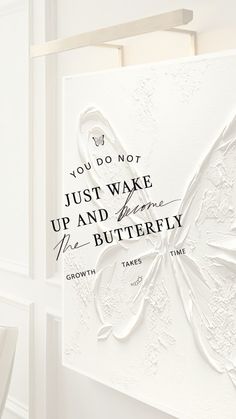 a white butterfly is on the wall next to a sign that says, you do not just wake up and be butterfly