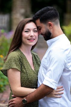 a man and woman embracing each other in front of some flowers on a sunny day