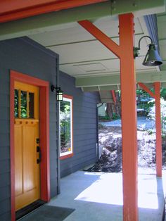 an orange door is on the side of a gray house