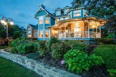 a large blue house sitting on top of a lush green field