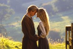 a man and woman standing next to each other on top of a grass covered field