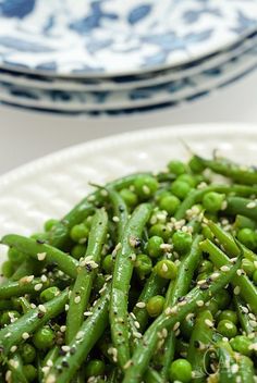 a white plate topped with green beans and sesame seeds