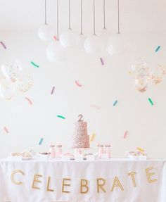 a celebration table with confetti and balloons on the wall in the back ground