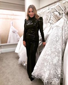 a woman standing in front of some wedding dresses