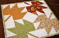 a close up of a quilt on a wooden table with an orange and green flower