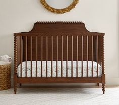 a baby crib in a white room with a mirror on the wall above it