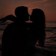 a couple kissing on the beach at sunset