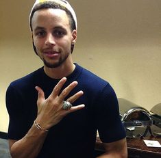 a man with a ring on his finger standing in front of a mirror and making the peace sign