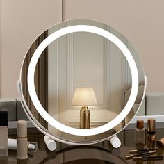 a round mirror sitting on top of a table next to a lamp and other items