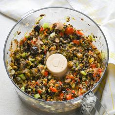 a food processor filled with chopped vegetables on top of a white table cloth next to a yellow towel