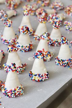 there are many white cones with colorful sprinkles on top of each one