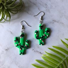 a pair of green cactus earrings sitting on top of a table