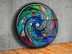 a circular stained glass piece on a wall next to a wooden floor and concrete wall