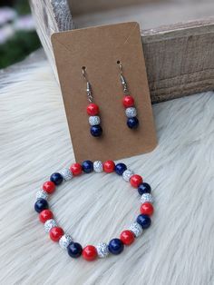 This patriotic stretch bracelet and earrings set features 8mm round red glass beads, 8mm round rhinestone silver beads, and 8mm round blue lapis lazuli beads. The bracelet measures 7.5 inches, and the earrings hang 2 inches on silver colored ear hooks. Lapis Lazuli Beads, Blue Lapis Lazuli, Blue Lapis, Ear Hook, Red Glass, Red White And Blue, Stretch Bracelet, Earrings Set, Stretch Bracelets