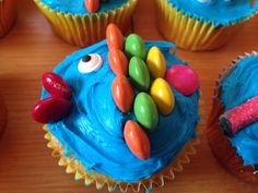 cupcakes with blue frosting and candy decorations on them are sitting on a table