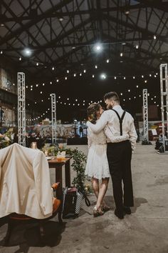 a man and woman standing next to each other in front of a table with flowers