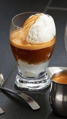 an ice cream sundae in a glass bowl with spoons next to it on a table