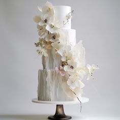 a three tiered cake with white flowers on top