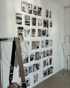 a white wall with many pictures on it and a guitar in the foreground,