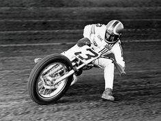 a man riding on the back of a motorcycle down a dirt road