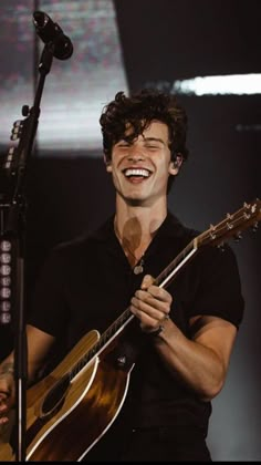 a man holding a guitar and singing into a microphone