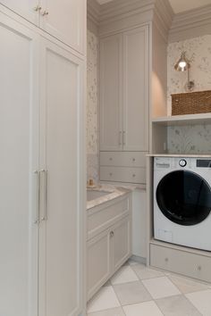 a washer and dryer in a white laundry room with patterned wall paper on the walls