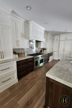 a large kitchen with white cabinets and wood flooring on the countertops, along with an island