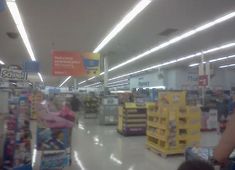 the interior of a grocery store with people walking around and shopping carts in the aisle