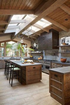 a large kitchen with wooden floors and an island in the center, surrounded by windows