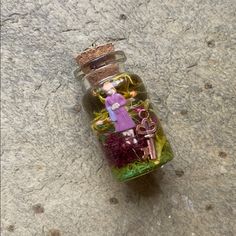 a glass bottle filled with lots of tiny items on top of a stone floor next to a wall