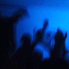 blurry image of people dancing in the dark with their hands up and arms raised