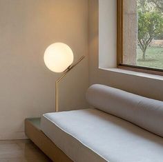 a white couch sitting under a window next to a lamp