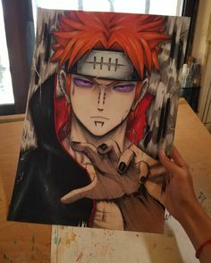 a person holding up a drawing of an anime character with red hair and black eyes