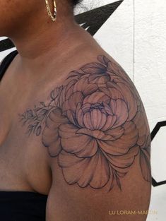 a woman's shoulder with a flower tattoo on her left arm and the upper half of her body