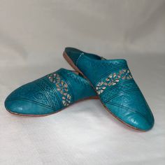 Women’s Leather Shoes 39 Hand Crafted Stamped Slip On Turquoise Blue Designed In Moroccan Aztec Boho Tribal Pattern. Delicate Embossed Patterns: The Finely Stamped Patterns Add A Touch Of Elegance And Authenticity To This Slipper, Making It One Of A Kind, Slip On Style With Flat Heel And Rounded Toe. Leather: Designed In Leather, This Shoe Slipper Combines Durability And Comfort To Provide You With An Exceptional Experience. Size Eu 39 - Translates To Us 9 Nwot - Mark At Heel Interior As Shown B Blue Leather Mules With Flat Heel, Blue Leather Flat Heel Mules, Blue Slip-on Leather Shoes With Rubber Sole, Blue Leather Shoes With Flat Heel, Spring Blue Closed Toe Leather Shoes, Blue Leather Shoes With Round Toe For Summer, Blue Closed Toe Leather Shoes For Spring, Casual Blue Mules With Leather Footbed, Blue Slip-on Leather Shoes With Flat Heel