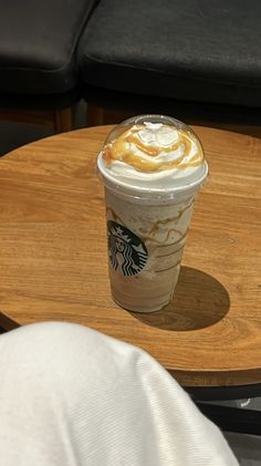 a cup of coffee sitting on top of a wooden table next to a black chair