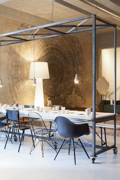 a dining room table with chairs and lamps on the ceiling in an industrial style setting