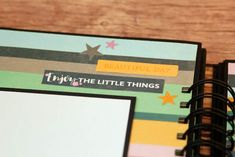 a close up of a planner book on a wooden table with paper and scissors next to it