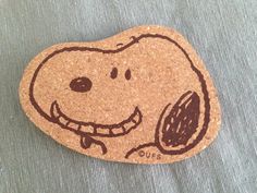 a cork coaster with a drawing of a smiling dog on it's back side