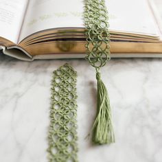 a book with some tassels on top of it next to an open book