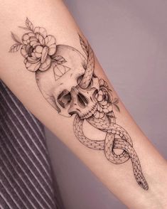 a woman's arm with a skull and snake tattoo on the left inner forearm