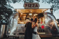 a bride and groom kissing in front of a food truck