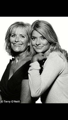 two women standing next to each other with their arms around one another and smiling at the camera