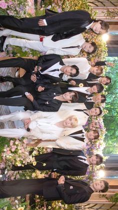 several people in suits and ties standing next to each other with flowers all around them