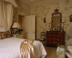 a bed sitting in a bedroom next to a dresser under a mirror on top of a wall