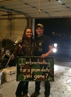 a man and woman standing next to each other holding a sign that says, i've been hunting for a prom date you game?