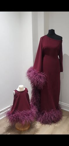 a dress with purple feathers on it and a mannequin's head next to it