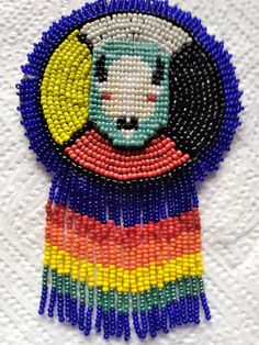 a beaded brooch with a cat on it's face and rainbow colors