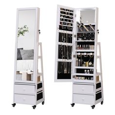 a white jewelry cabinet sitting next to a mirror on top of a wooden stand with drawers