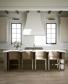 a kitchen with two ovens, chairs and a table in front of the stove